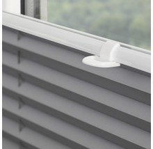 Detailní záběr šedé plisované žaluzie na okně s ovládacím prvkem