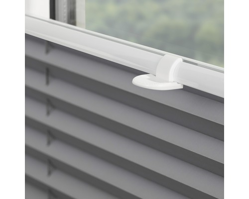 Detailní záběr šedé plisované žaluzie na okně s ovládacím prvkem