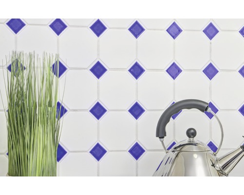 Dekorativní obklady s modrým kosočtvercovým vzorem, nerezová konvice a umělá rostlina