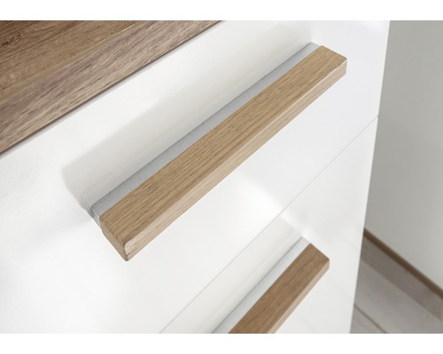 Detail bílé skříně s dřevěnými úchyty.