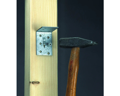 Úhelník se šroubem namontovaný na dřevě, vedle kladivo