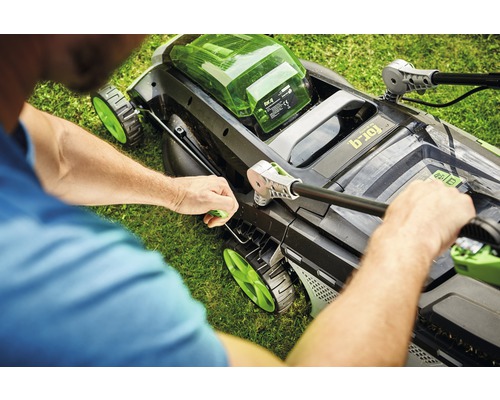 Muž montuje sekačku na trávu na zahradě.