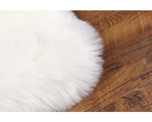 Bílý koberec z umělé kožešiny na dřevěné podlaze