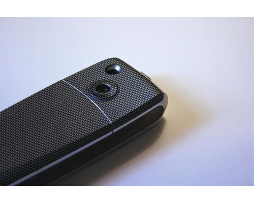 Detailní pohled na elektronické zařízení se vzorem uhlíkových vláken a dvěma vybráními.