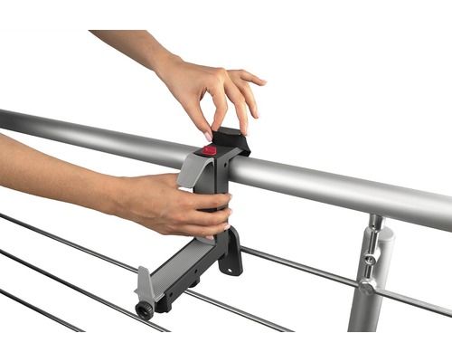 Osoba připevňuje držák sušáku prádla k zábradlí