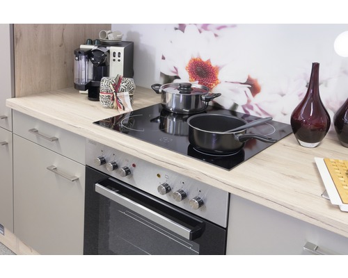 Kuchyňská scéna s kamny, varnými deskami, hrnci a kuchyňskými potřebami na světlé pracovní desce