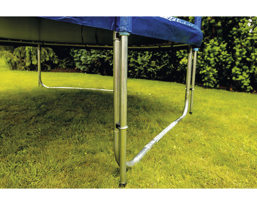 Detailní záběr trampolíny s kovovým rámem a nohama na zahradě.