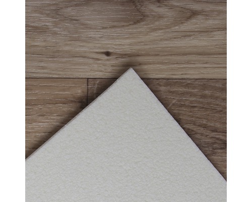 Detailní pohled na bílou vinylovou dlaždici na dřevěné podlaze.