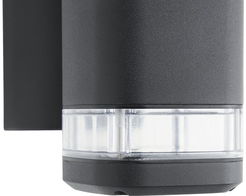 Detail černé venkovní nástěnné lampy s průhledným stínidlem.