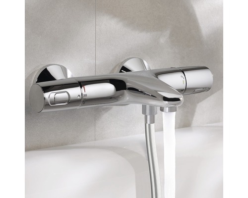 Termostatická baterie na stěnu v koupelně s tekoucí vodou.