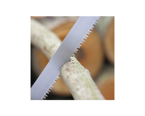 Ruční pila řeže větev.