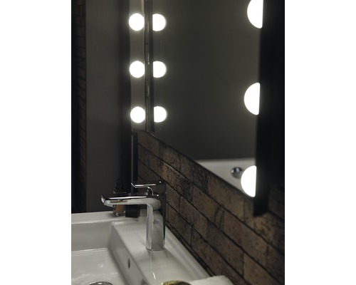 Umyvadlo v koupelně s baterií a osvětleným zrcadlem v designu cihel