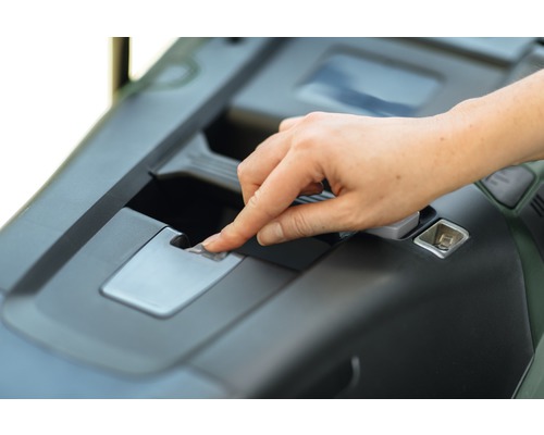 Ruka aktivuje odblokování na zahradním traktoru.