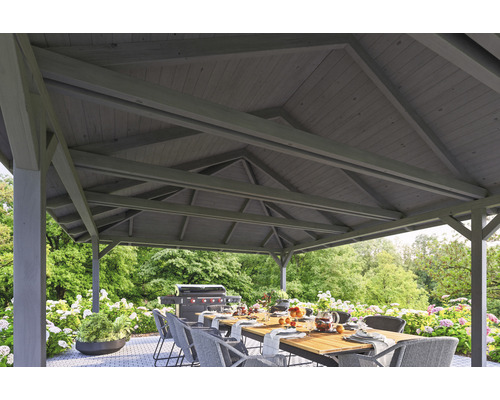 Pergola s dřevěnou střechou, jídelní stůl a gril na zahradě