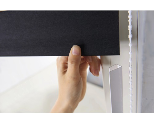 Detailní záběr osoby ovládající černou roletu s řetízkem