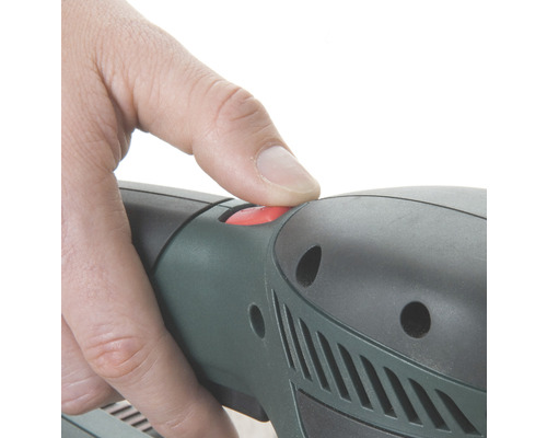 Detailní záběr ruky stisknutím červeného tlačítka na elektrickém nářadí.