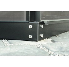 Detailní záběr rohu skleníku se šrouby na kamenné podlaze.