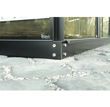 Detail kovového základu skleníku se šrouby na kamenné podlaze