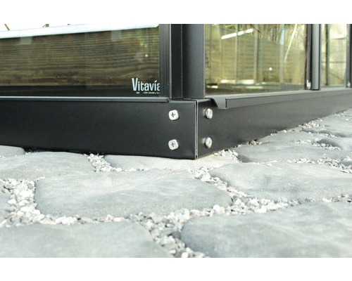 Detail kovového základu skleníku se šrouby na kamenné podlaze