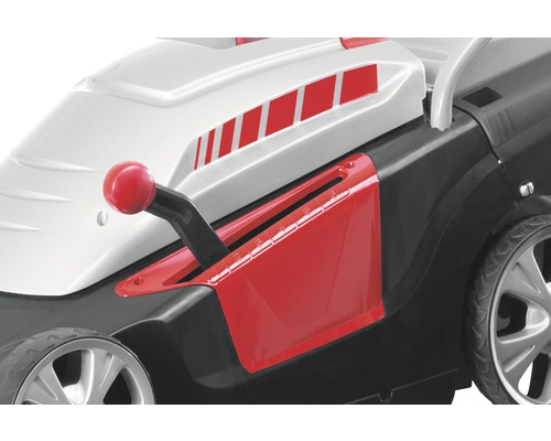 Detailní pohled na sekačku na trávu s červenou pákou pro nastavení výšky sečení