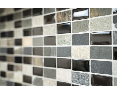 Mozaiková stěna s obdélníkovými dlaždicemi v různých odstínech šedé a texturách