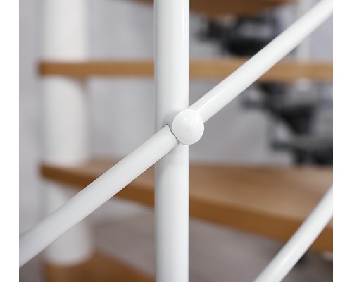 Detail bílého schodišťového zábradlí s dřevěnými schody v pozadí