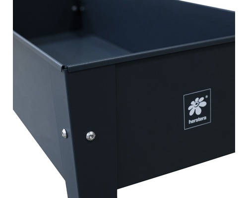 Detailní pohled na černý květináč s logem Herstera.