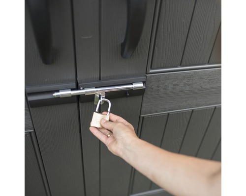 Osoba zamyká zahradní kůlnu visacím zámkem.