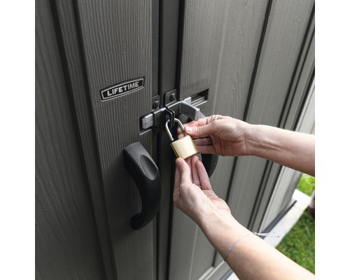 Osoba zamyká zahradní domek visacím zámkem