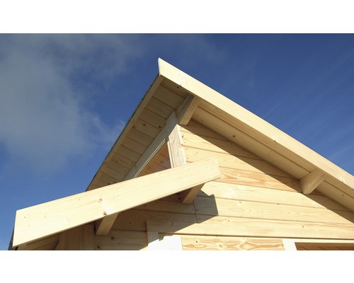 Detailní pohled na dřevěný dům s konstrukcí štítové střechy na pozadí modré oblohy