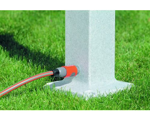 Zahradní hadice připojená k vodnímu sloupku na trávníku