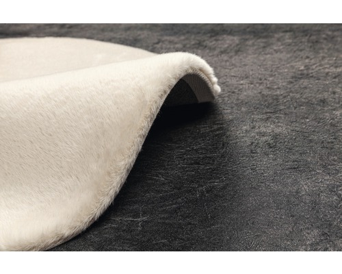 Detail kulatého, světlého koberce s vysokým vlasem