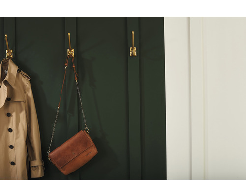 Scéna s trenčkotem a kabelkou zavěšenou na zlatých nástěnných háčcích