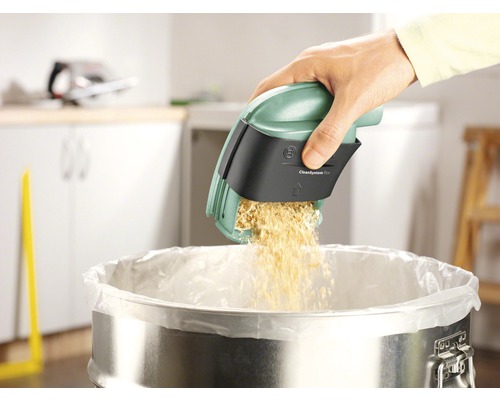 Osoba vyprazdňuje nádobu na prach z vysavače do koše