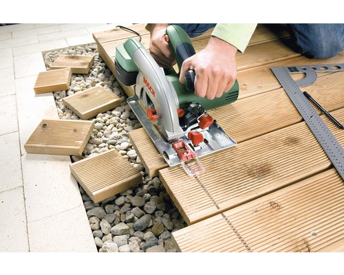 Osoba řeže dřevěnou desku ruční kotoučovou pilou