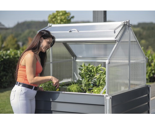 Zvýšený záhon s pařeništěm a žena, která pracuje na zahradě