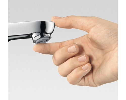 Detail ruky dotýkající se výtoku vodovodní baterie.