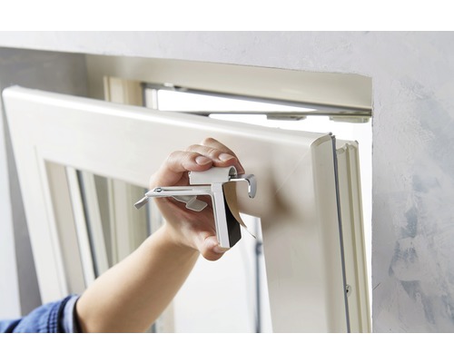 Osoba montuje okno pomocí upevňovací spony