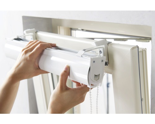 Osoba montuje roletu na okenní rám