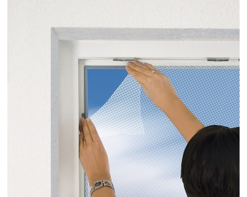 Osoba připevňuje síť proti hmyzu k oknu