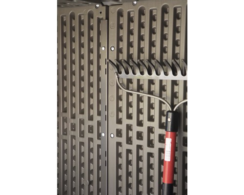 Detailní pohled na držák zahradního nářadí v zahradním domku s hráběmi.