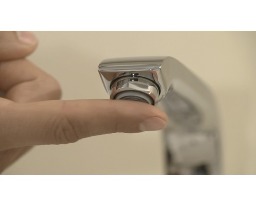 Detailní záběr ruky dotýkající se perlátoru vodovodní baterie