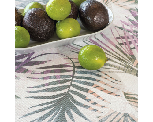 Avokáda a limetky na talíři na ubrusu se vzorem listů.