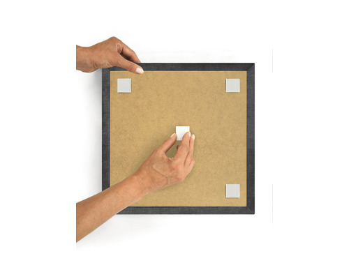 Osoba připevňuje lepicí podložky na fotorámeček