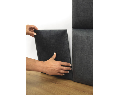 Osoba upevňuje akustický panel na stěnu