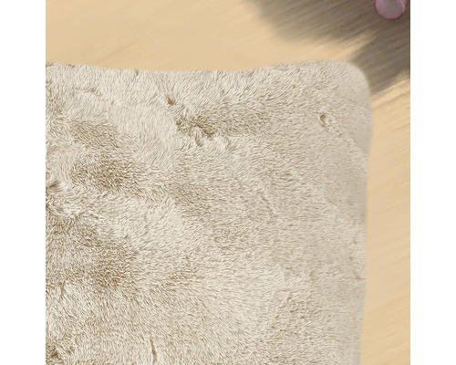 Detail béžového obdélníkového koberce s vysokým vlasem.