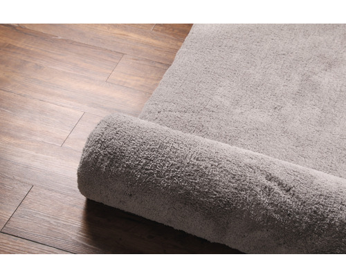 Látkový koberec, částečně srolovaný, na dřevěné podlaze