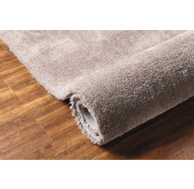 Srolovaný koberec s vysokým vlasem na dřevěné podlaze