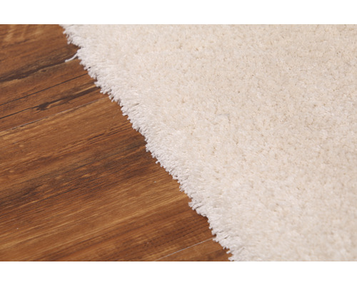 Detailní pohled na světlý koberec na dřevěné podlaze