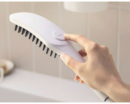 Ruka ovládá bílý kartáč s černými štětinami.